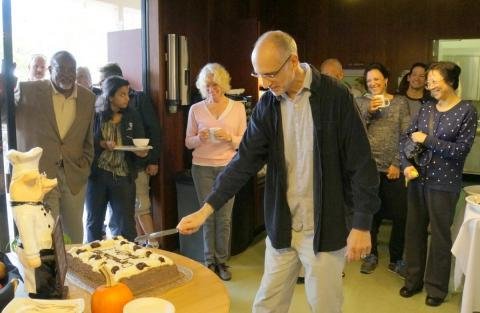 Marvin Gilens cutting his celebration cake with his colleagues